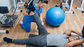 Healthcare worker helping patient stretch leg